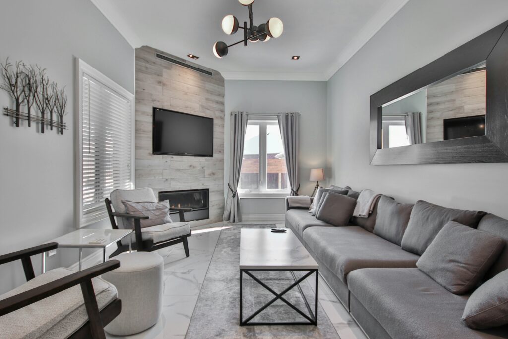 Modern living room with gray sofa, fireplace, and wall-mounted TV.