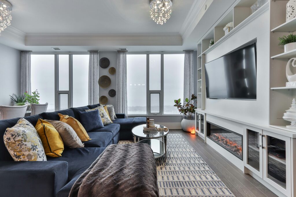 Modern living room with blue sectional sofa, fireplace, and large TV.
